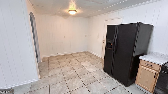 kitchen with light tile patterned floors, ornamental molding, black refrigerator with ice dispenser, and light brown cabinets