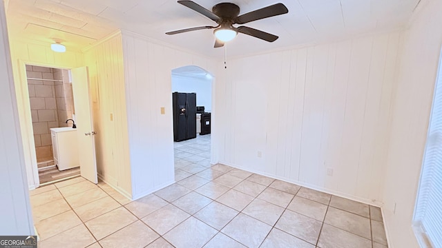 spare room featuring ceiling fan, wooden walls, washer / clothes dryer, and light tile patterned floors