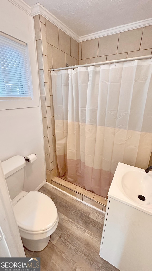 bathroom featuring wood-type flooring, vanity, walk in shower, toilet, and crown molding