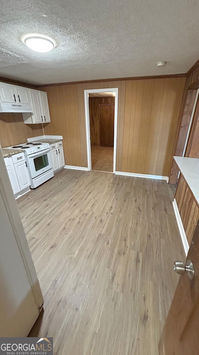 kitchen with wooden walls, a textured ceiling, white cabinets, white electric stove, and light wood-type flooring