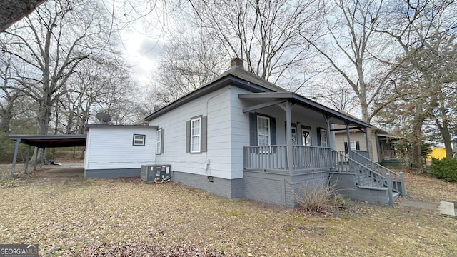 view of front of property featuring a carport, cooling unit, and covered porch