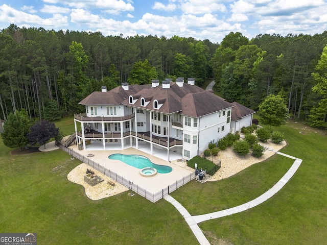 rear view of property featuring a patio area, a balcony, and a lawn