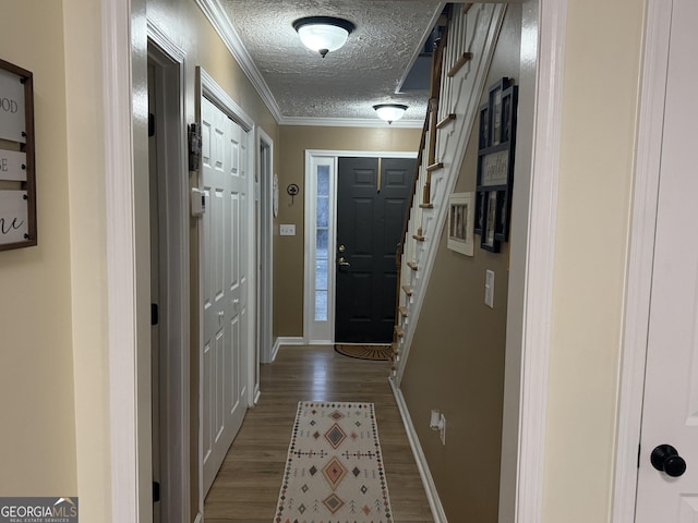 doorway with hardwood / wood-style flooring, crown molding, and a textured ceiling