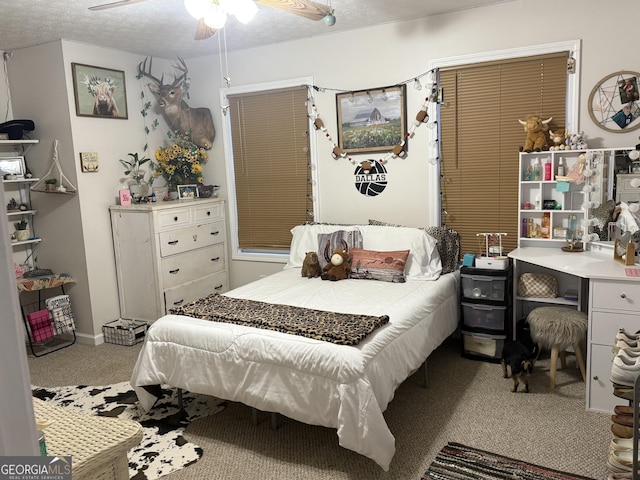 carpeted bedroom with ceiling fan and a textured ceiling