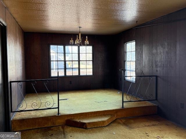 unfurnished bedroom featuring a notable chandelier and wooden walls