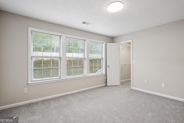 3742 Berkeley Xing, Duluth, GA 30096 - unfurnished bedroom featuring a textured ceiling, visible vents, baseboards, carpet floors, and a walk in closet