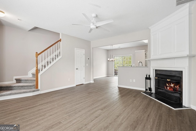 3742 Berkeley Xing, Duluth, GA 30096 - unfurnished living room with visible vents, ceiling fan with notable chandelier, wood finished floors, stairs, and a lit fireplace