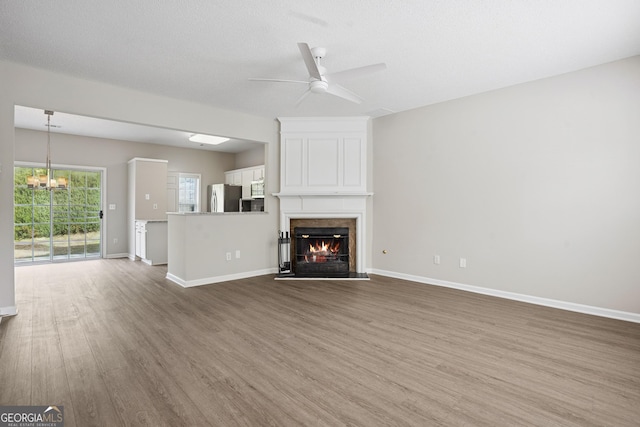 3742 Berkeley Xing, Duluth, GA 30096 - unfurnished living room featuring a fireplace, wood finished floors, baseboards, and ceiling fan with notable chandelier