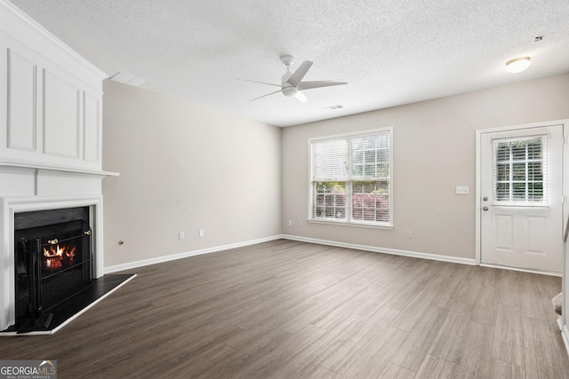 3742 Berkeley Xing, Duluth, GA 30096 - unfurnished living room featuring a fireplace, wood finished floors, a healthy amount of sunlight, and a ceiling fan