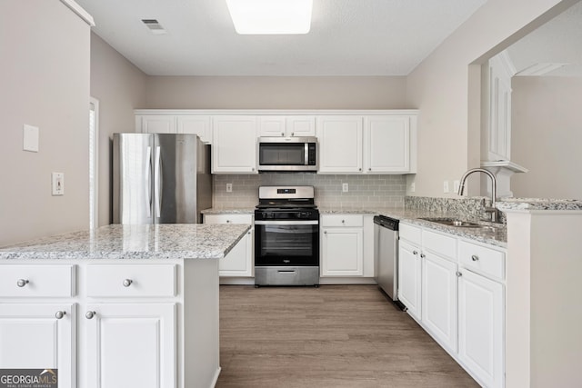 3742 Berkeley Xing, Duluth, GA 30096 - kitchen featuring white cabinets, light wood-style flooring, a sink, decorative backsplash, and appliances with stainless steel finishes