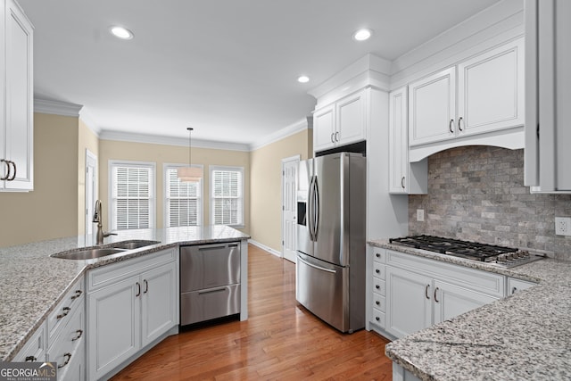 kitchen with sink, crown molding, hanging light fixtures, stainless steel appliances, and white cabinets