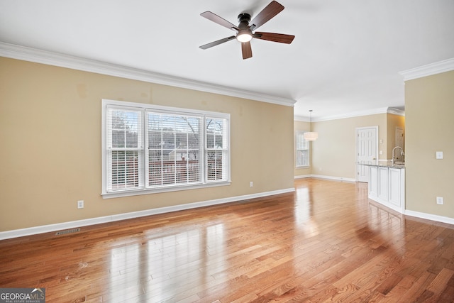 unfurnished living room featuring sink, crown molding, light hardwood / wood-style flooring, and ceiling fan