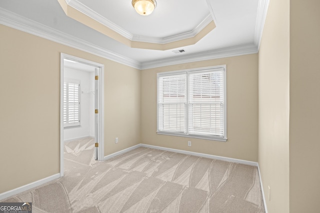 carpeted empty room with crown molding and a tray ceiling