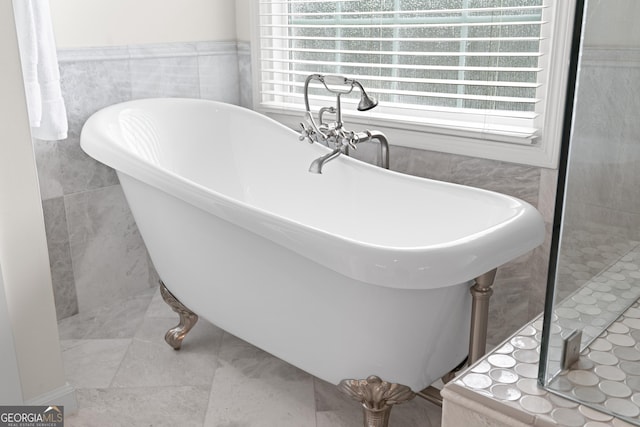 bathroom featuring tile walls and a tub to relax in