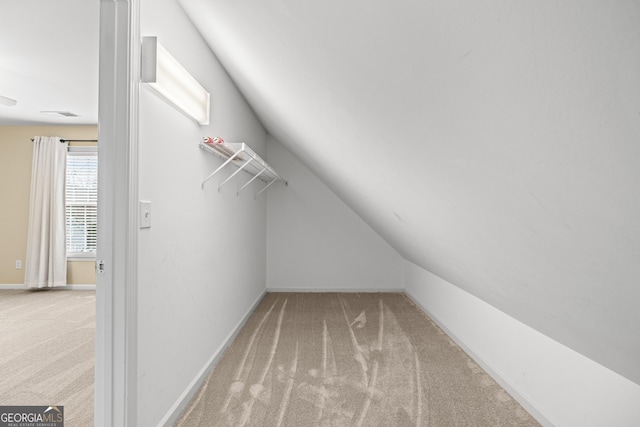 spacious closet featuring vaulted ceiling and light carpet