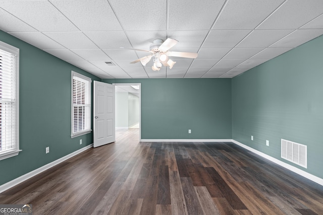 unfurnished room with ceiling fan, dark hardwood / wood-style floors, and a drop ceiling