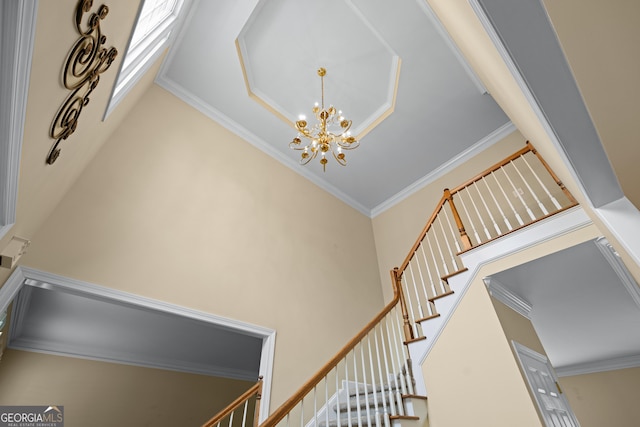 stairs with a notable chandelier, ornamental molding, and a high ceiling