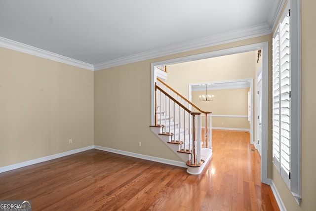 entrance foyer with ornamental molding, hardwood / wood-style floors, and a notable chandelier