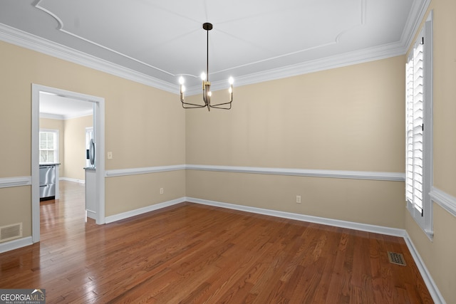 empty room with wood-type flooring, ornamental molding, and a notable chandelier