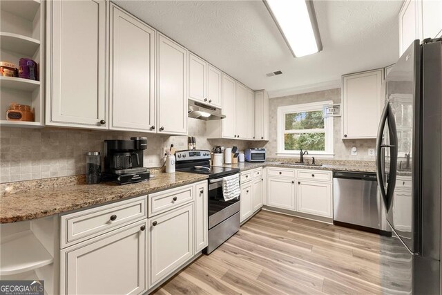 kitchen featuring white cabinetry, stainless steel appliances, light stone countertops, light hardwood / wood-style floors, and sink