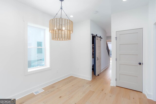 unfurnished dining area featuring light hardwood / wood-style flooring and a barn door