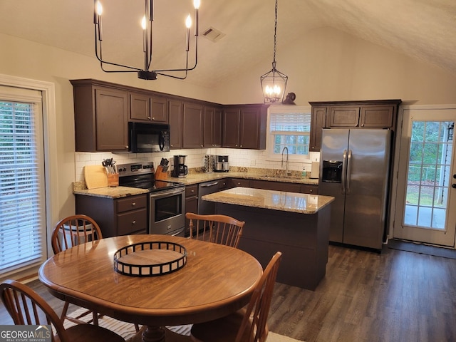 kitchen featuring decorative light fixtures, decorative backsplash, stainless steel appliances, and a kitchen island