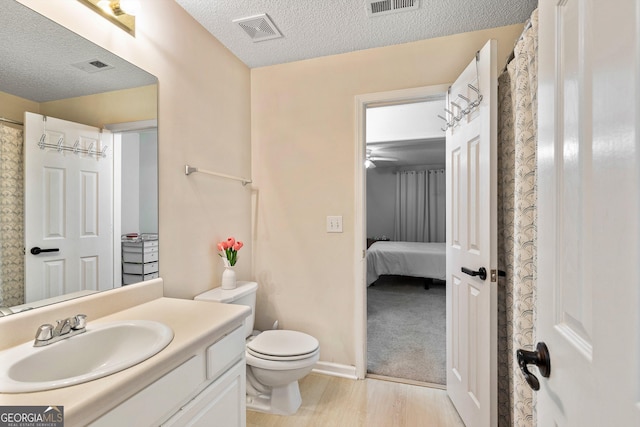 bathroom featuring vanity, hardwood / wood-style floors, toilet, and a textured ceiling