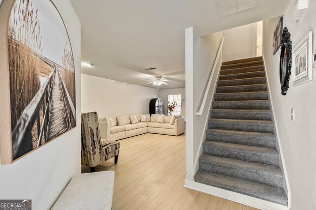 staircase with hardwood / wood-style flooring and ceiling fan