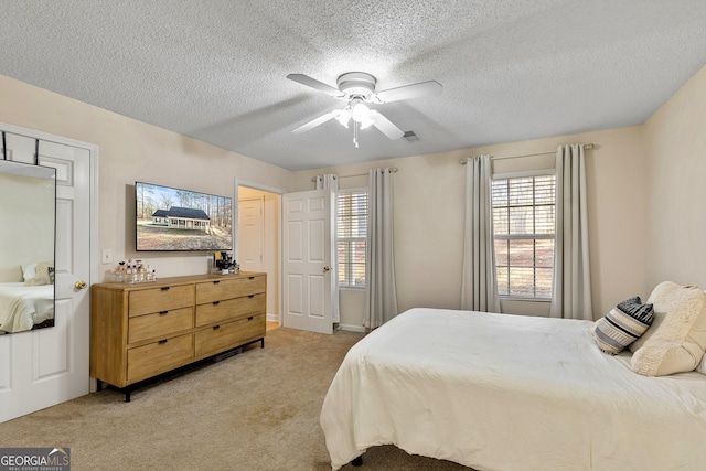 carpeted bedroom with ceiling fan and a textured ceiling