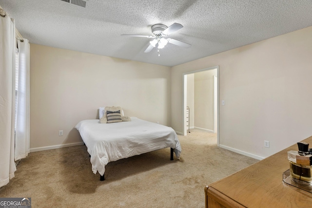 bedroom featuring ceiling fan, light colored carpet, and a textured ceiling