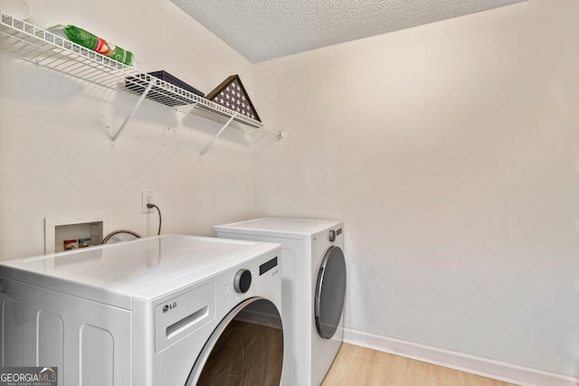 clothes washing area featuring independent washer and dryer, a textured ceiling, and light wood-type flooring