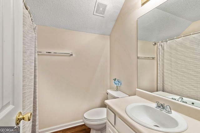 bathroom featuring vanity, toilet, vaulted ceiling, and a textured ceiling