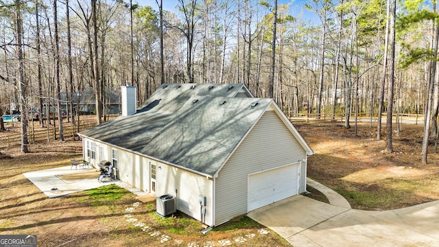 view of side of home with a garage and central air condition unit