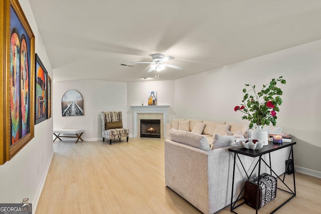 living room featuring ceiling fan, wood-type flooring, and a fireplace