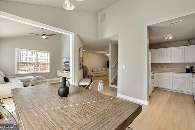 dining space featuring ceiling fan, vaulted ceiling, and light hardwood / wood-style flooring