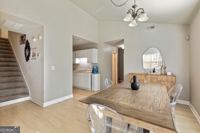 dining area featuring lofted ceiling, sink, a chandelier, and light wood-type flooring