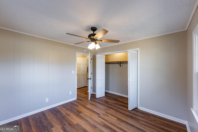 unfurnished bedroom featuring ceiling fan, crown molding, dark wood-type flooring, a textured ceiling, and a closet