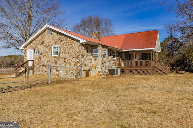 rear view of property featuring central AC unit, a yard, and covered porch