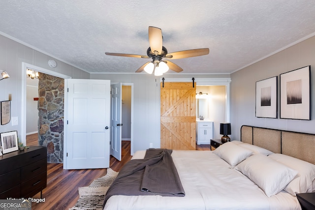 bedroom with dark hardwood / wood-style flooring, ornamental molding, a barn door, and a textured ceiling