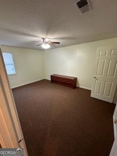 empty room featuring dark carpet and ceiling fan