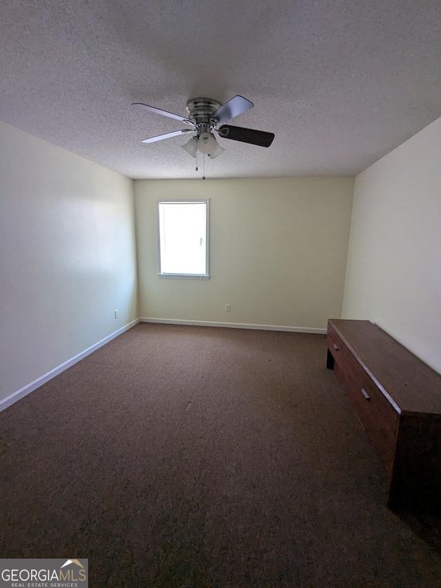 spare room featuring ceiling fan, a textured ceiling, and dark colored carpet