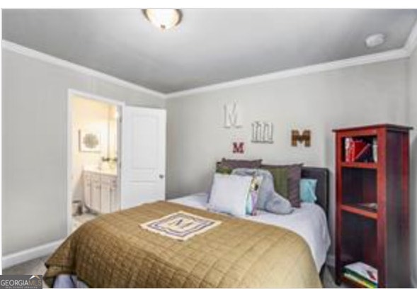 bedroom with ornamental molding, carpet flooring, and ensuite bath