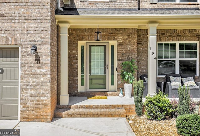 view of exterior entry with a garage and covered porch