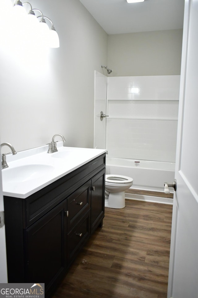 full bathroom with vanity, toilet,  shower combination, and wood-type flooring