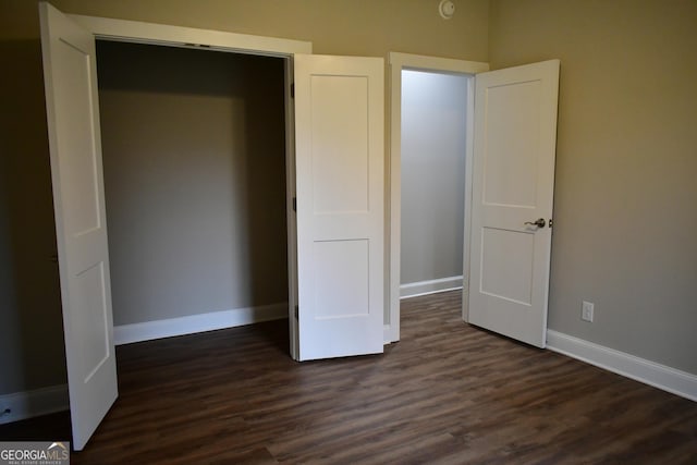 unfurnished bedroom with dark wood-type flooring and a closet