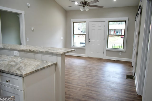 kitchen featuring white cabinetry, a barn door, dark wood-type flooring, and ceiling fan