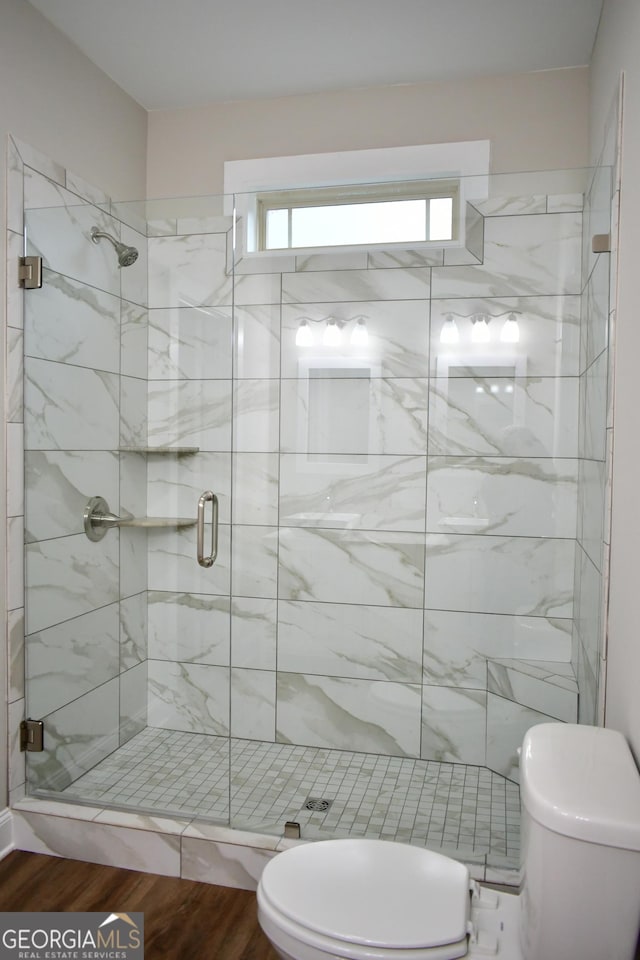 bathroom with walk in shower, toilet, and hardwood / wood-style floors