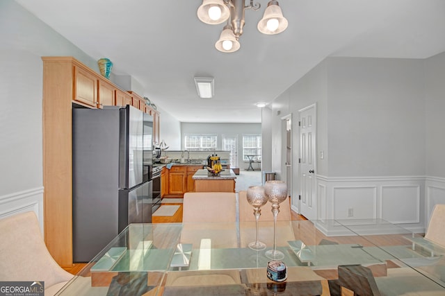 dining area with an inviting chandelier, a decorative wall, and a wainscoted wall