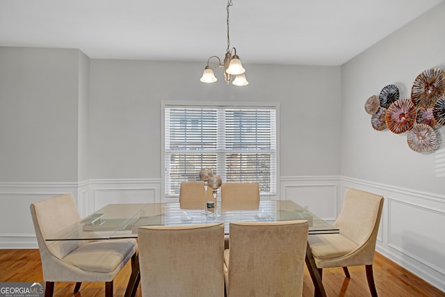 dining room with a chandelier, wainscoting, and wood finished floors