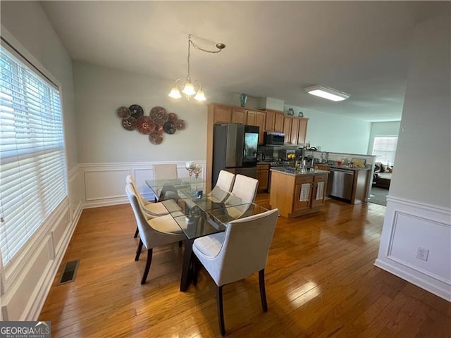 dining space with light hardwood / wood-style flooring and a chandelier